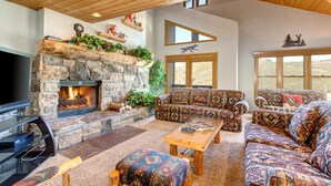 A living room with a stone fireplace, a television, a sofa, and a coffee table.