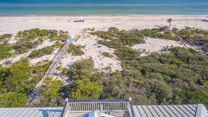 A beach view with a wooden walkway leading to the water, surrounded by vegetation. - Private Pool, Elevator, Sleeps 20, Bob Sikes Cut! (St. George Island)