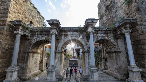 Un'antica arcata in pietra con colonne, che conduce a una scala.