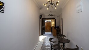 Un corridoio con zona pranzo, tavolo e sedie, un lampadario e un cartello appeso al muro.
