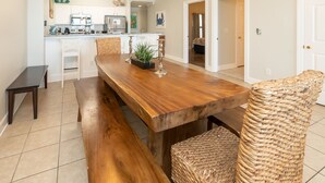 Uma sala de jantar com mesa de madeira, bancos e cadeiras de vime.