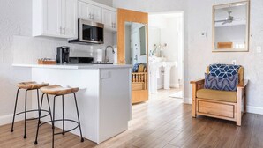 A modern kitchen with white cabinets, a central island with stools, a microwave, and a sink. - Luxury Studio | Pool, Spa & Fireplace (St. George)
