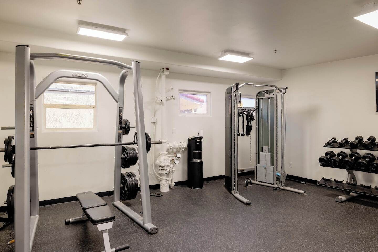Une salle de sport équipée de matériel de musculation, d’un banc et d’haltères.