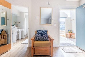A room with a wooden chair, a large mirror, and a view of a bathroom and outdoor area. - Poolside Retreat | Spa & Pickleball (St. George)