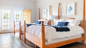 A double bed with a wooden frame, two bedside tables, and a large window with a view of greenery. - Luxury Studio | Pool, Spa & Fireplace (St. George)