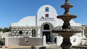 A white building with a bell tower and a fountain in front. The sign reads "Amira Resort & Spa". - Luxury Studio | Pool, Spa & Fireplace (St. George)