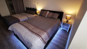 Un dormitorio con dos camas, un armario, una mesita de noche con lámpara y adornos de mariposas en la pared.