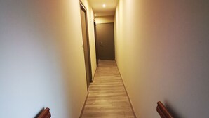 Un estrecho pasillo bien iluminado con suelo de madera y paredes blancas.