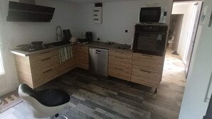 Cocina compacta con armarios de madera, lavavajillas, microondas y fregadero.
