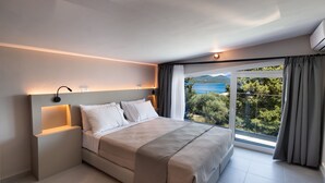Een moderne slaapkamer met een groot bed, nachtkastjes en uitzicht op zee.