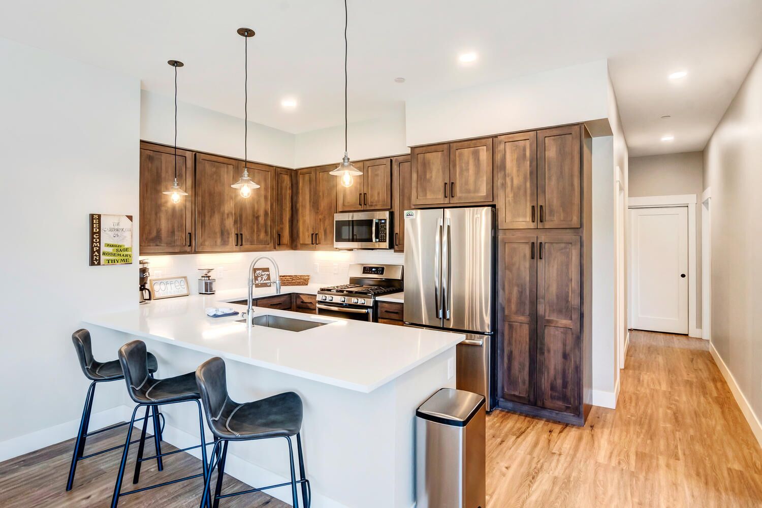 A modern kitchen with a central island, stainless steel appliances, and wooden cabinets.