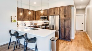 Una cocina moderna con una isla grande, electrodomésticos de acero inoxidable y armarios de madera oscura.