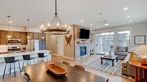 Una cocina moderna con comedor, chimenea y sala de estar con sofá y mesa de centro.
