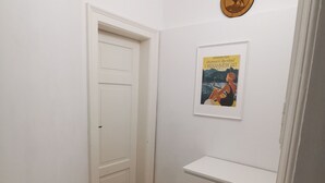 Ein Flur mit weißen Wänden, Holzboden, einer weißen Tür und einer weißen Kommode mit Schubladen.