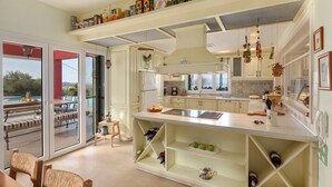 A spacious kitchen with a large island, open shelving, and a view of the outdoors.