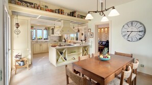 A spacious kitchen with a central island, wooden dining table, and chairs.