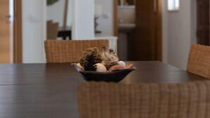 Un coin repas avec une table en bois foncé, des chaises en osier et un vase contenant des objets décoratifs.