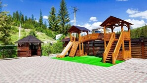 A wooden play structure with a slide and a small shelter. - Villa Nikoletta (Bukovel)