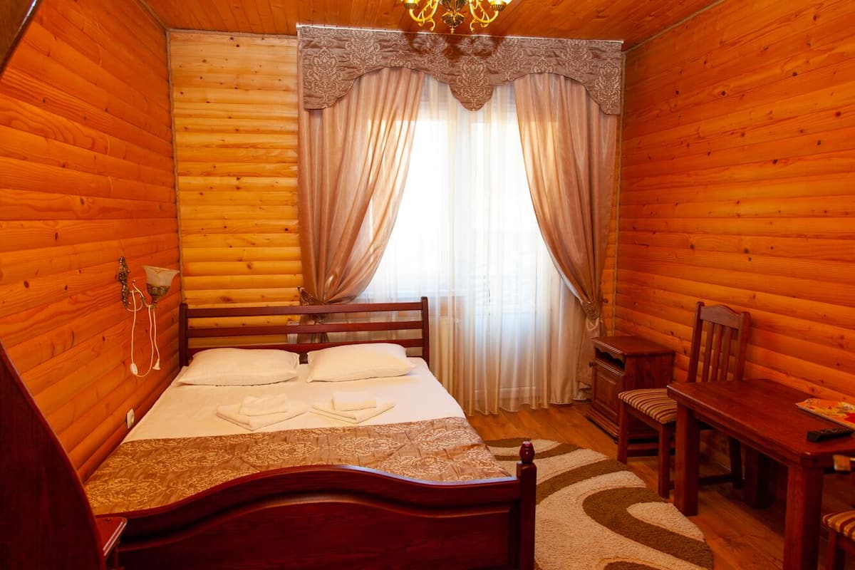 A wooden cabin room with a bed, a wooden table, and a chair.