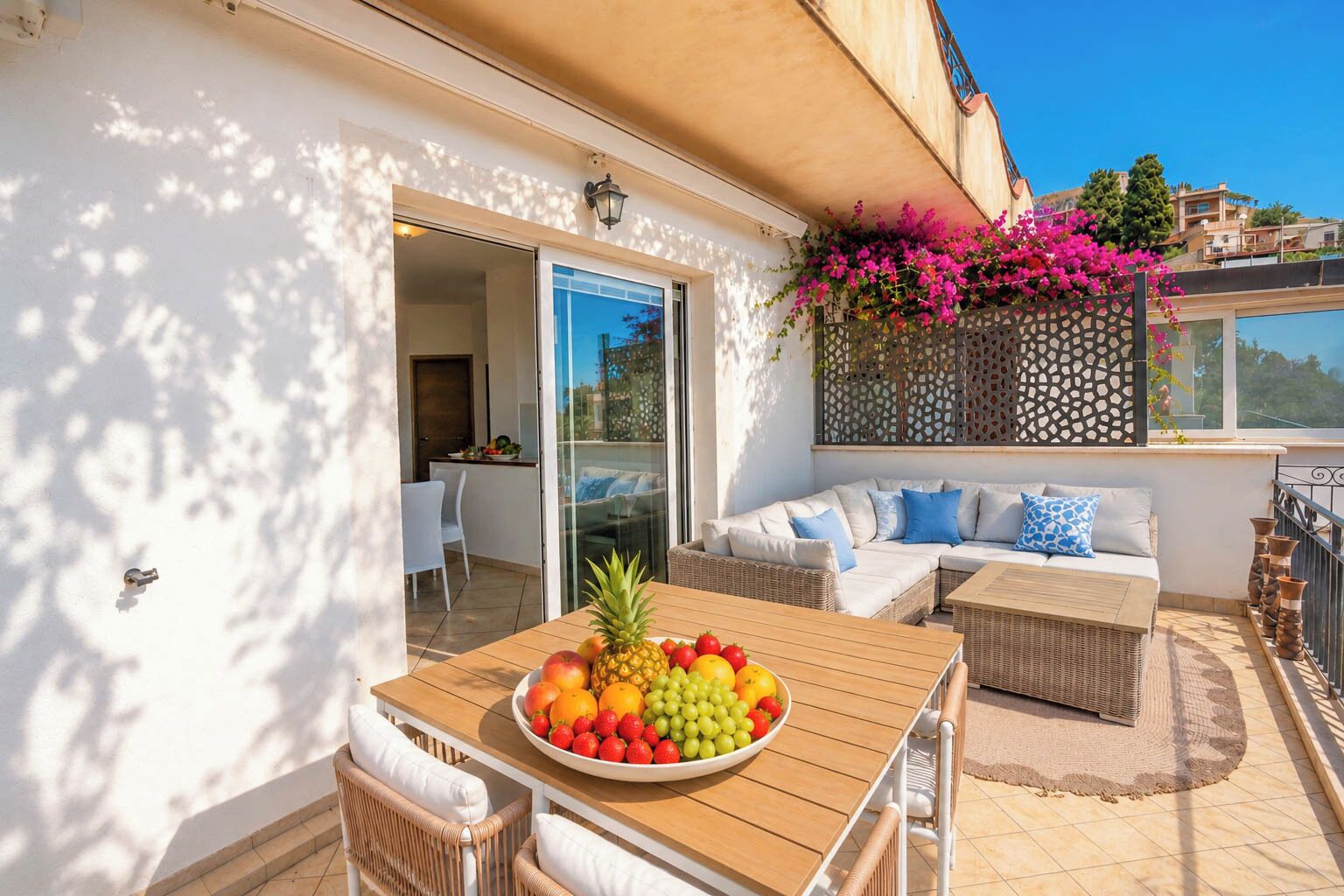 An outdoor patio with a dining table, wicker furniture, and a fruit bowl.