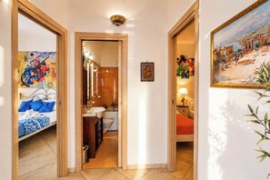 A hotel room with a bed, a bathroom, and a hallway leading to another room. - Cloe House: Panoramic Terrace with Ocean View (Taormina)