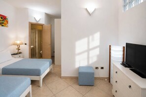 A hotel room with two beds, a television, a desk with a lamp, and a window with blinds. - Cloe House: Panoramic Terrace with Ocean View (Taormina)