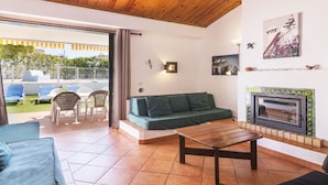 A cozy living room with a wooden ceiling, a green sofa, a wooden coffee table, and a fireplace. - Wonderful private villa for 8 guests with private pool, TV and patio (Albufeira)
