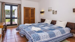 A bedroom with a large bed, a wooden wardrobe, a desk, and a view of a pool through a glass door. - Wonderful private villa for 8 guests with private pool, TV and patio (Albufeira)