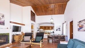 A spacious living area with a wooden ceiling, a television, a fireplace, and a dining area with wooden furniture. - Wonderful private villa for 8 guests with private pool, TV and patio (Albufeira)