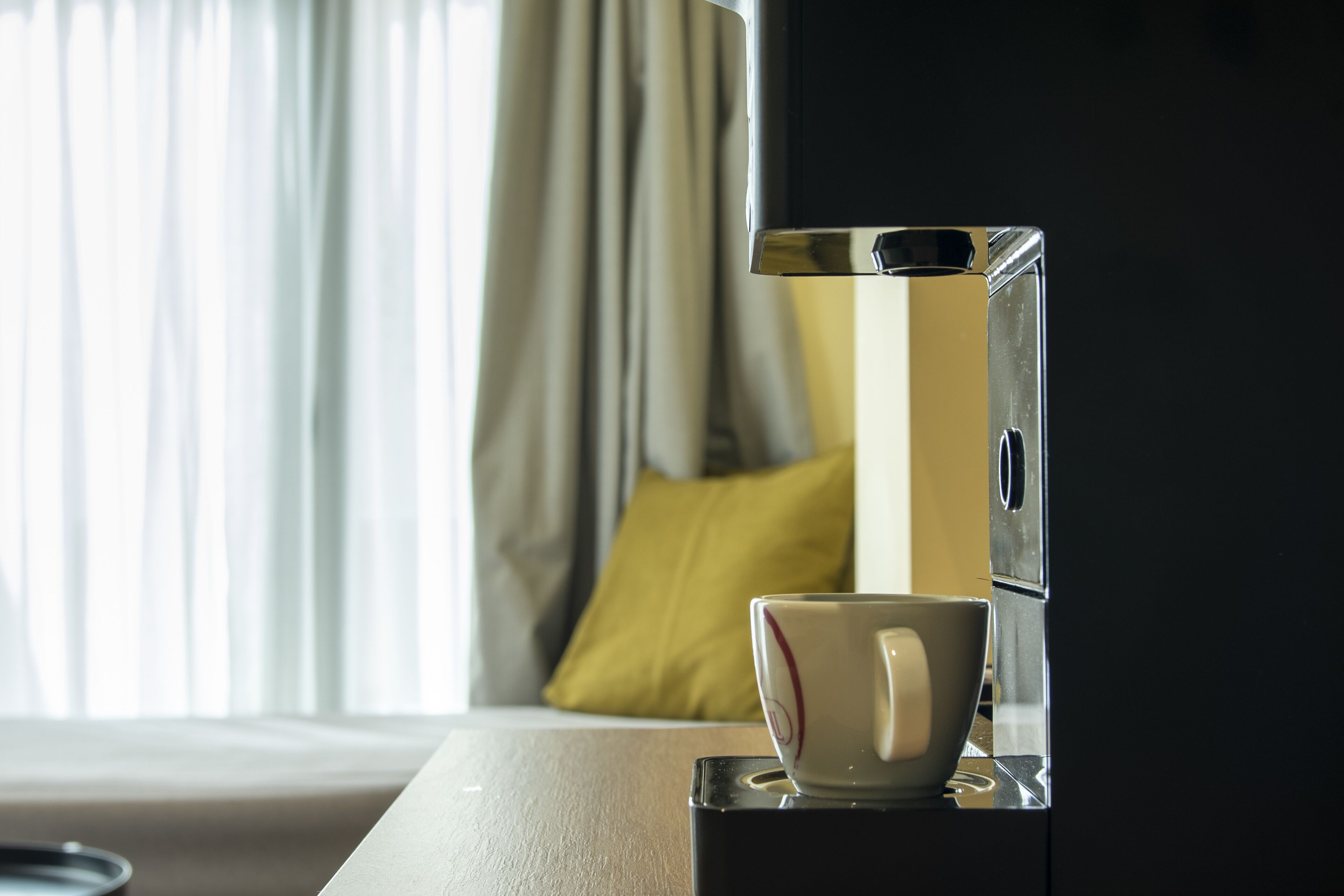 A coffee machine and cup on a table in a hotel room.