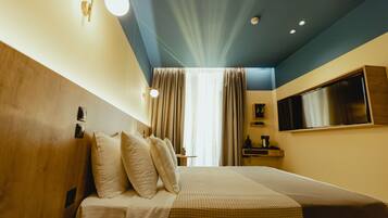 Deluxe kamer | Luxe beddengoed, donsdekens, een minibar, een kluis op de kamer