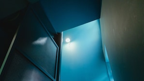 Uma escadaria com corrimão de metal e uma parede iluminada em azul.