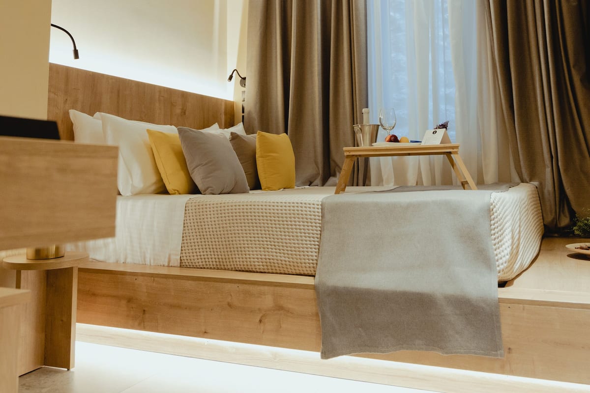 A modern bedroom with a wooden bed, a bedside table, and a window with curtains.