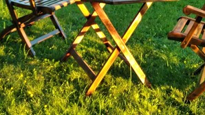 A wooden table with a bottle of wine and two glasses, set outdoors on a grassy area with chairs. - Beautifully Renovated, French Barn, Pet Friendly with WIFI (Saint-Plantaire)