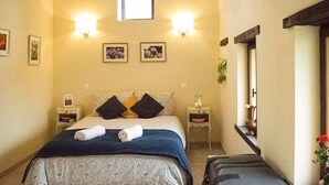 A bedroom with a bed, two bedside tables, a nightstand, a suitcase, and a window. - Beautifully Renovated, French Barn, Pet Friendly with WIFI (Saint-Plantaire)