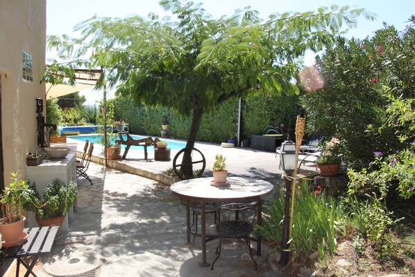 A patio with a round table and chairs, surrounded by potted plants and a swimming pool. - VILLA PROVENÇALE with private pool (between Aix and Marseille) (VELAUX)