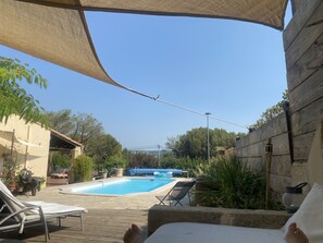 A pool area with lounge chairs and a pergola.