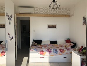 A bedroom with a bed, a wardrobe, a bedside table, a hanging light fixture, and a wall-mounted air conditioner. - VILLA PROVENÇALE with private pool (between Aix and Marseille) (VELAUX)