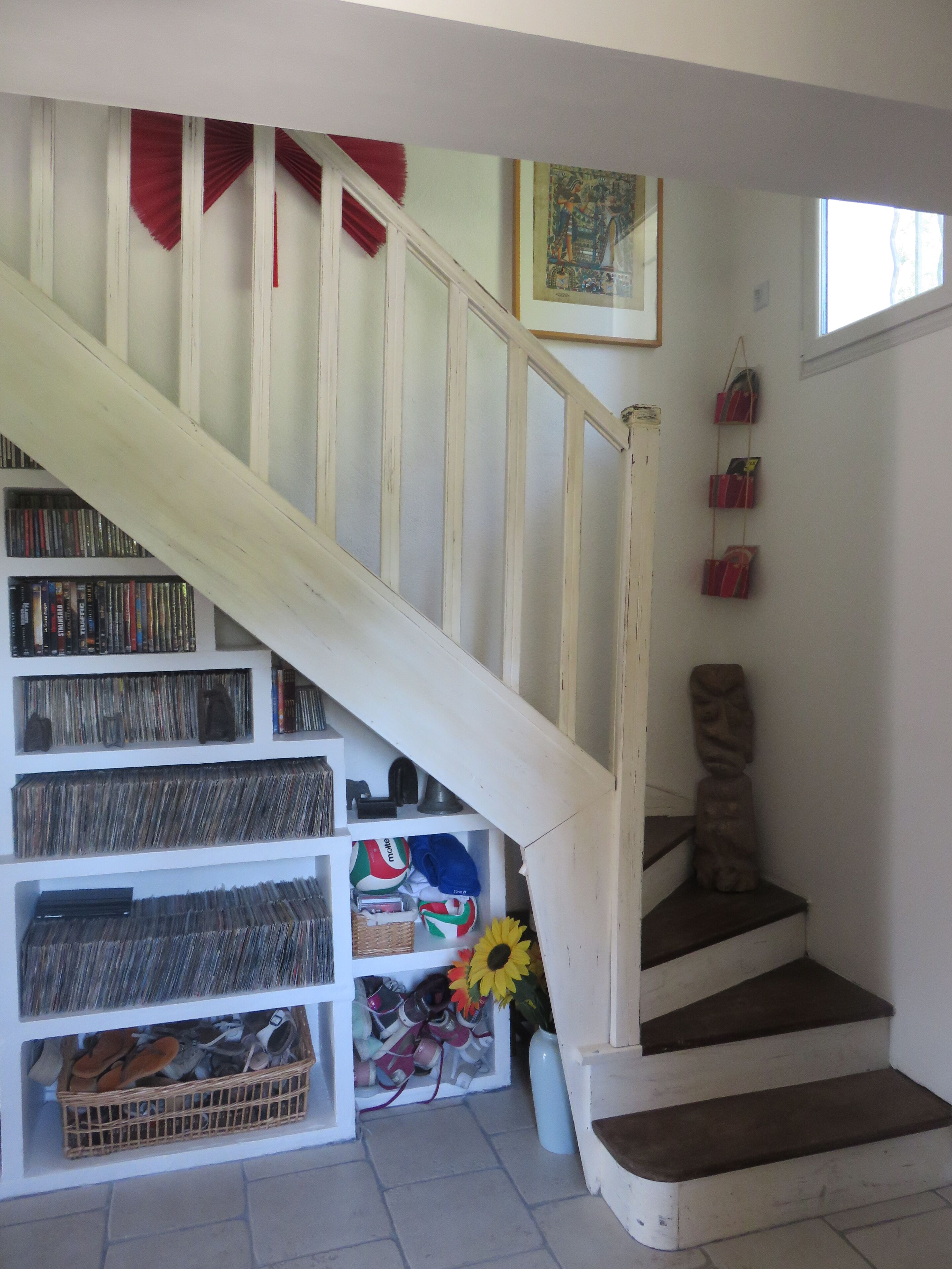 A staircase with a white railing leading to a landing with a bookshelf filled with books and DVDs.