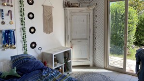 A bedroom with a bed, a white wardrobe, a macrame wall hanging, and a door leading to a garden. - VILLA PROVENÇALE with private pool (between Aix and Marseille) (VELAUX)