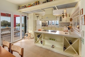 Una cocina moderna con una isla grande, almacenamiento empotrado para vinos y vistas a un área de estar exterior.