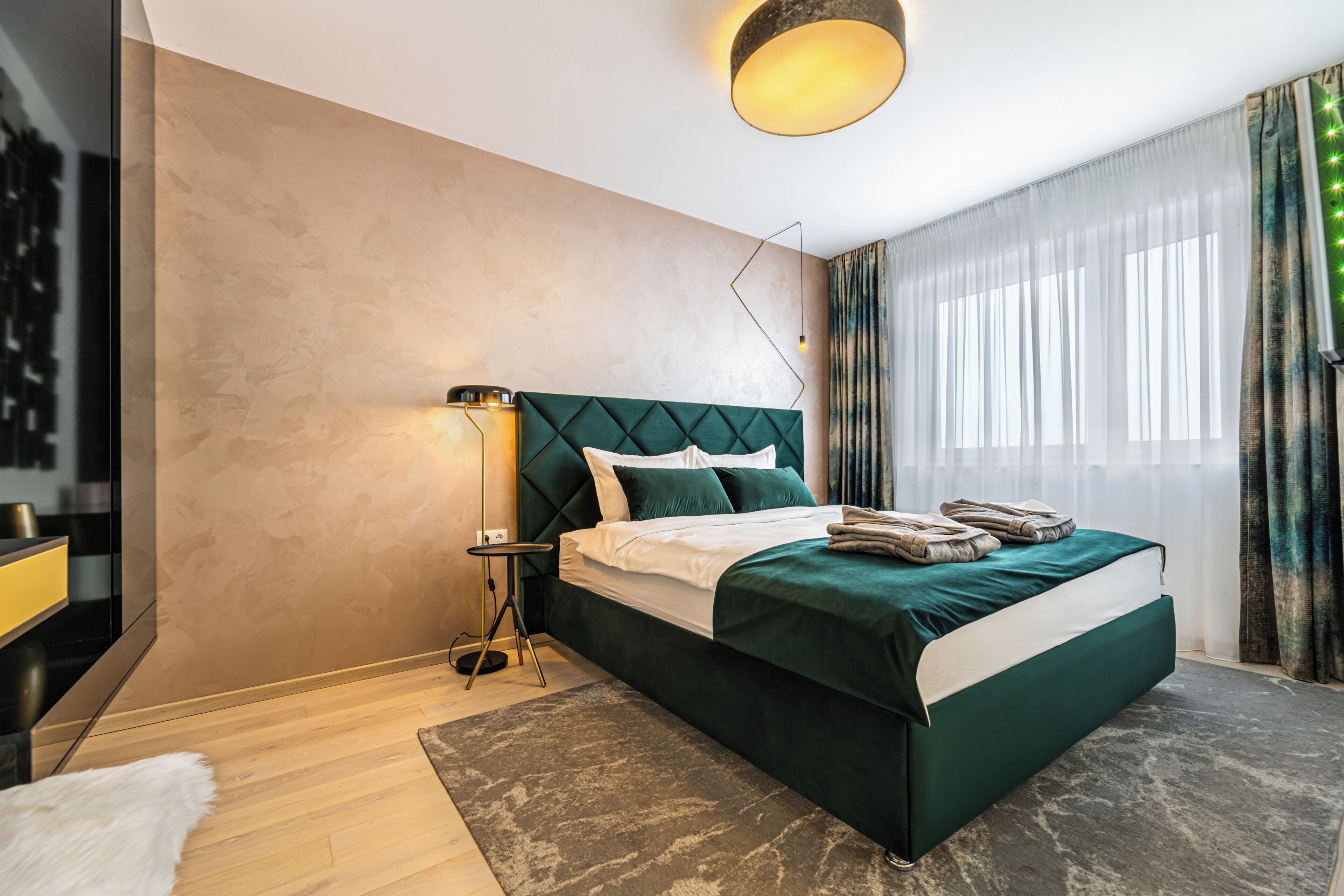 A modern bedroom with a large bed, a bedside table, and a floor lamp.