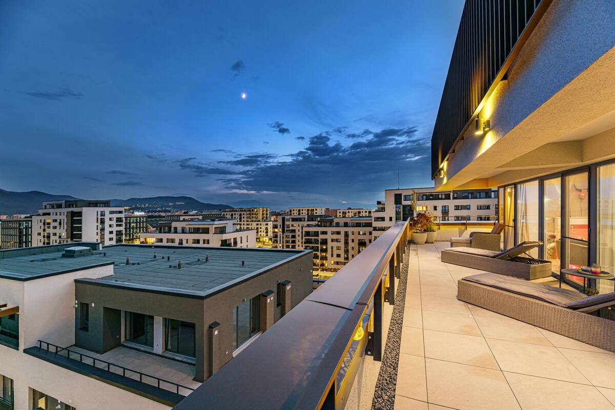 Terraza en la azotea con mobiliario exterior y vista panorámica de la ciudad.
