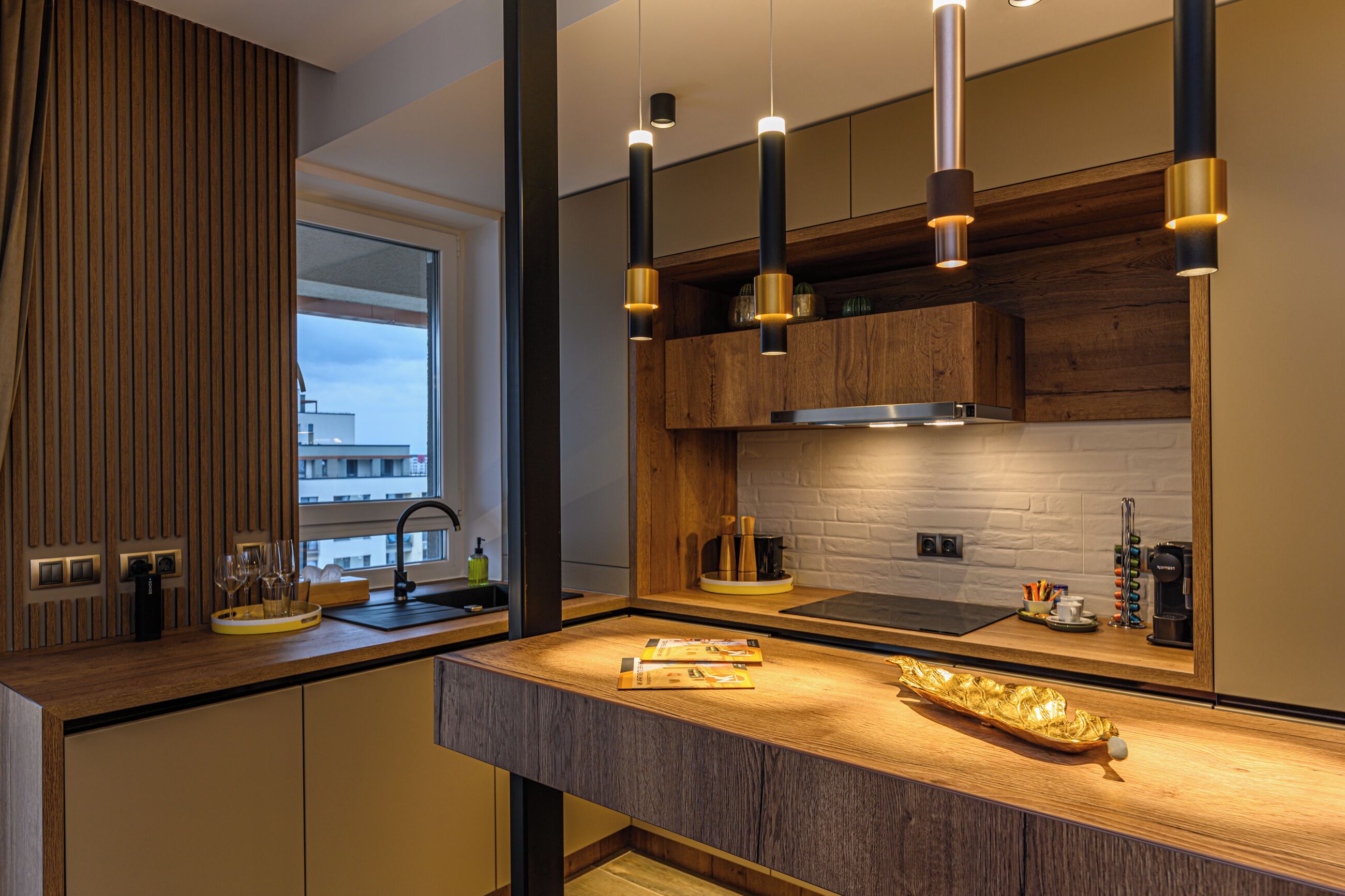 A modern kitchen with a wooden countertop, built-in cabinets, and pendant lighting.