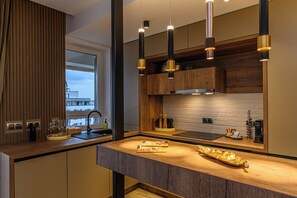 Une cuisine moderne dotée d’un plan de travail en bois, d’armoires encastrées et de luminaires suspendus.