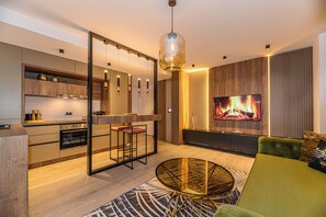 Une cuisine moderne dotée d’un îlot central, un coin repas avec une table en verre et un espace de vie comprenant un canapé et une cheminée.
