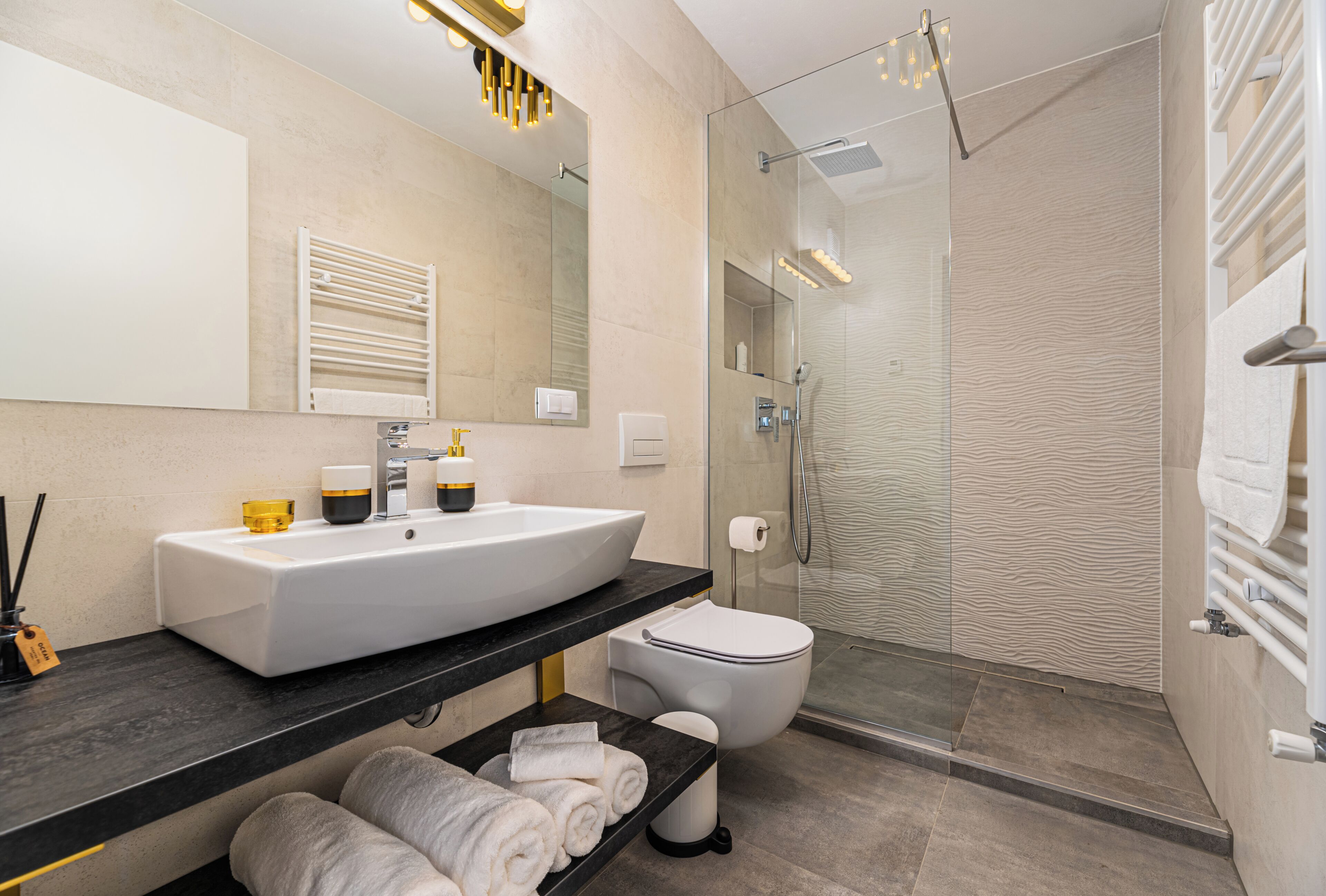 A modern bathroom with a large white sink, a glass shower enclosure, and a built-in toilet.