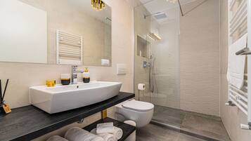 A modern bathroom with a large white sink, a glass shower enclosure, and a built-in toilet.