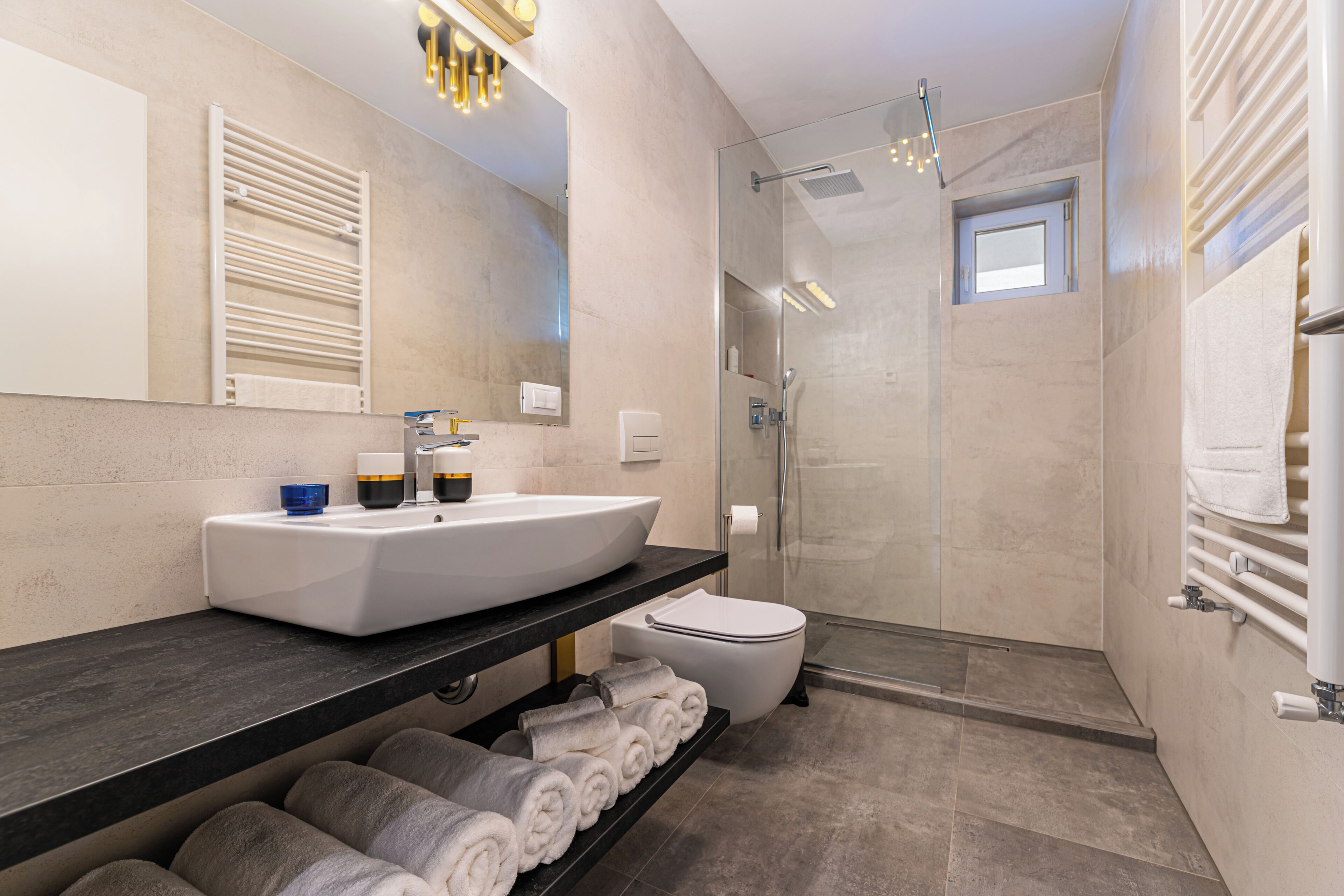 A modern bathroom with a large sink, toilet, and shower area.