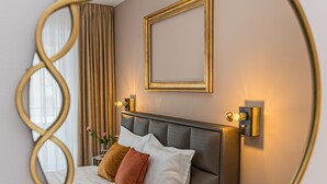 A bedroom with a bed, a wall-mounted light, and a framed picture. - MK Apartments Brasov (Brasov)